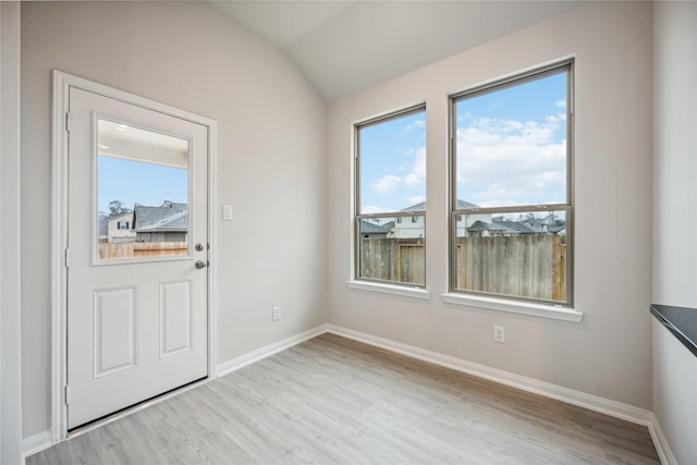 doorway to outside with a wealth of natural light, lofted ceiling, and light wood-type flooring