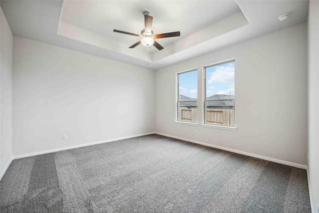 spare room featuring carpet flooring, ceiling fan, and a tray ceiling