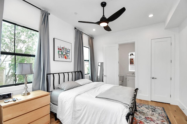 bedroom with ensuite bathroom, light hardwood / wood-style flooring, ceiling fan, and sink