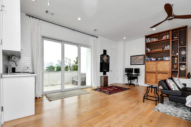 living room with ceiling fan, light hardwood / wood-style floors, and sink