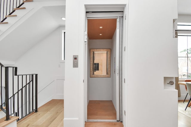 hallway featuring light hardwood / wood-style floors and vaulted ceiling