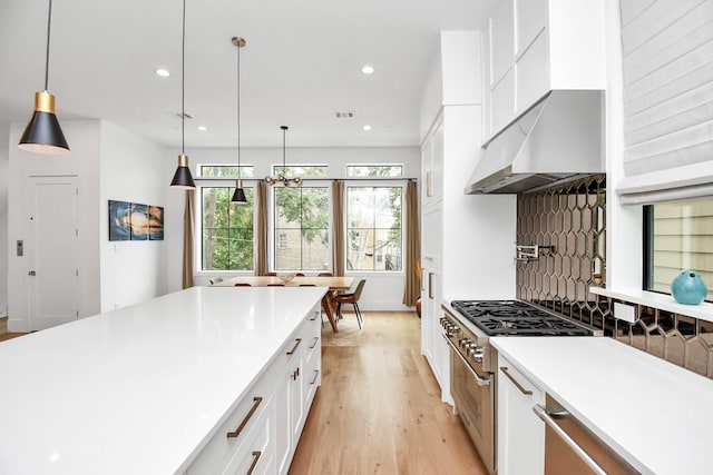 kitchen with range hood, pendant lighting, high end stainless steel range, white cabinets, and light wood-type flooring