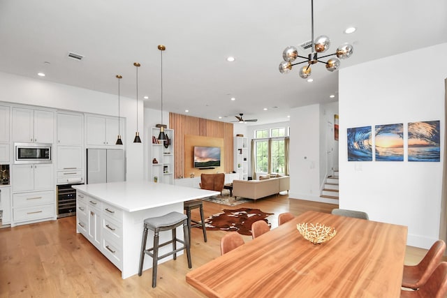 kitchen with built in appliances, ceiling fan with notable chandelier, pendant lighting, and a kitchen island