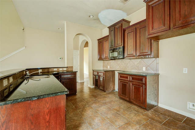 kitchen featuring tasteful backsplash, dark stone counters, and sink