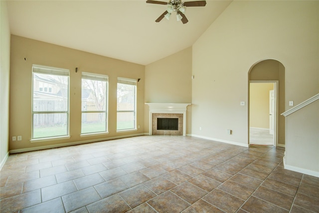 unfurnished living room featuring ceiling fan, high vaulted ceiling, and a tiled fireplace