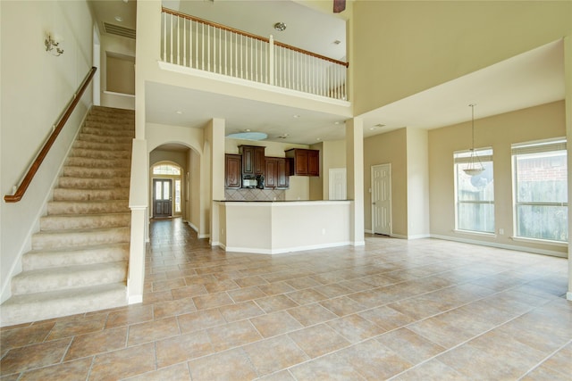 unfurnished living room featuring a towering ceiling