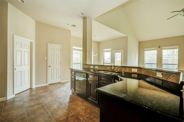 kitchen featuring dishwasher, a wealth of natural light, sink, and dark stone counters