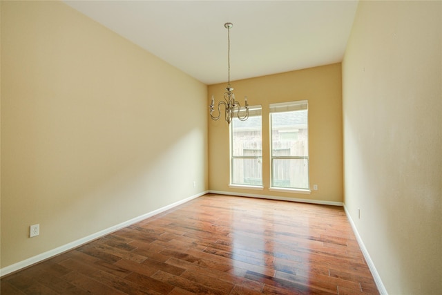 spare room with hardwood / wood-style flooring and a notable chandelier