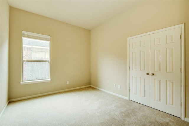 unfurnished bedroom featuring light carpet and a closet