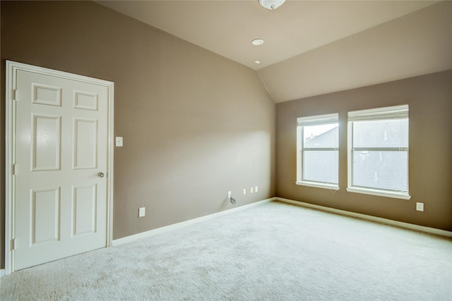 carpeted empty room featuring vaulted ceiling