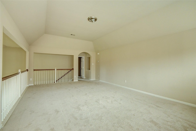 carpeted spare room featuring vaulted ceiling