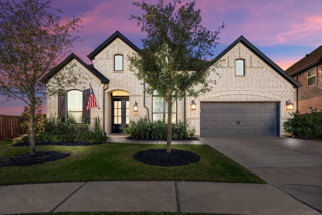 french provincial home featuring a yard and a garage