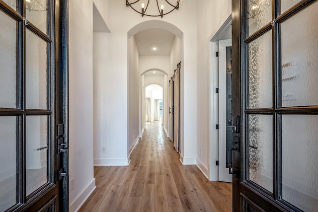 hall featuring light wood-type flooring and an inviting chandelier