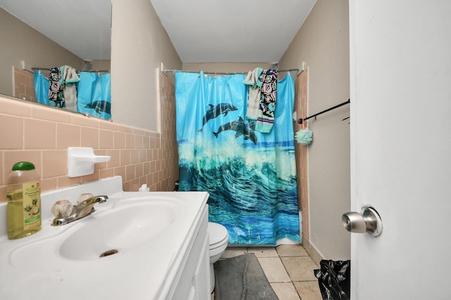 bathroom featuring vanity, tile patterned flooring, toilet, walk in shower, and tile walls