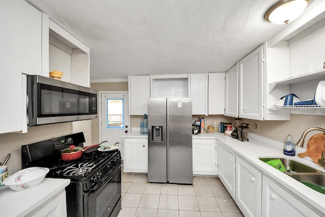 kitchen featuring appliances with stainless steel finishes, light tile patterned floors, white cabinetry, and sink