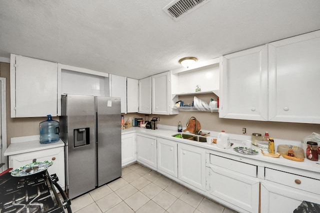 kitchen featuring white cabinetry, stainless steel fridge, sink, and light tile patterned floors