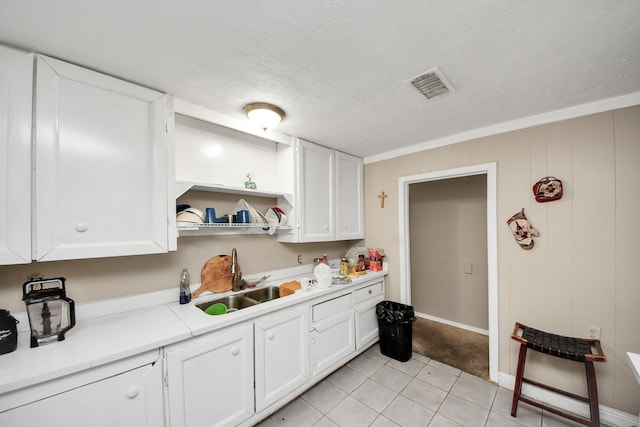 kitchen with light tile patterned floors, a textured ceiling, white cabinetry, and sink