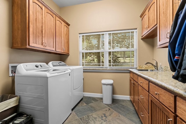 clothes washing area with separate washer and dryer, sink, and cabinets