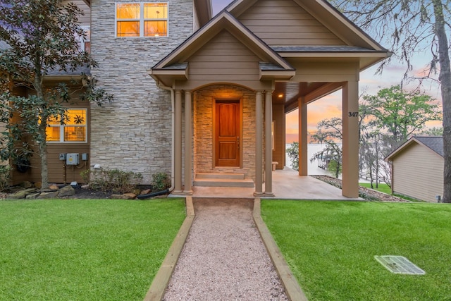 exterior entry at dusk featuring a yard