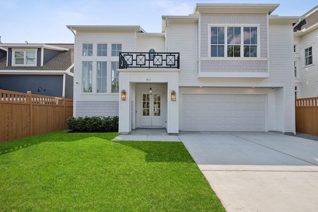 view of front facade with a balcony, a front yard, and a garage