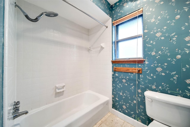 bathroom featuring toilet, tiled shower / bath combo, and tile patterned flooring