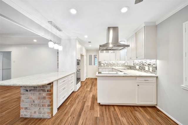 kitchen with decorative light fixtures, white cabinetry, island exhaust hood, kitchen peninsula, and light wood-type flooring