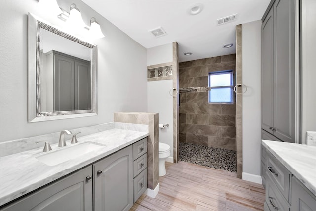 bathroom featuring vanity, tiled shower, and toilet