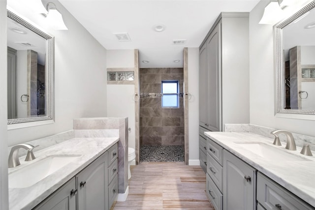 bathroom with vanity, a tile shower, and toilet