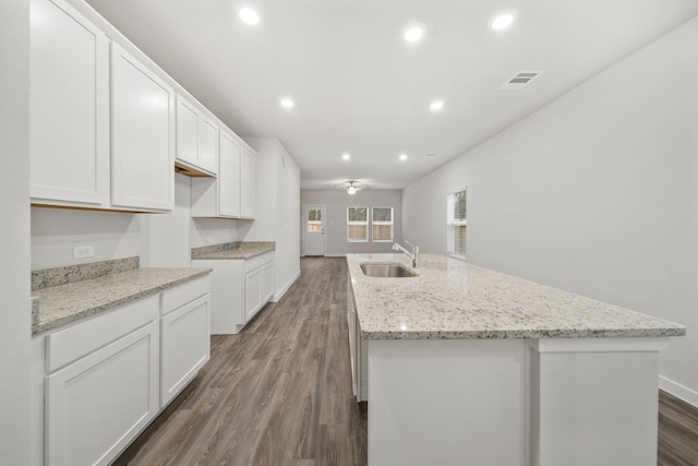 kitchen with sink, dark hardwood / wood-style flooring, a kitchen island with sink, and white cabinets