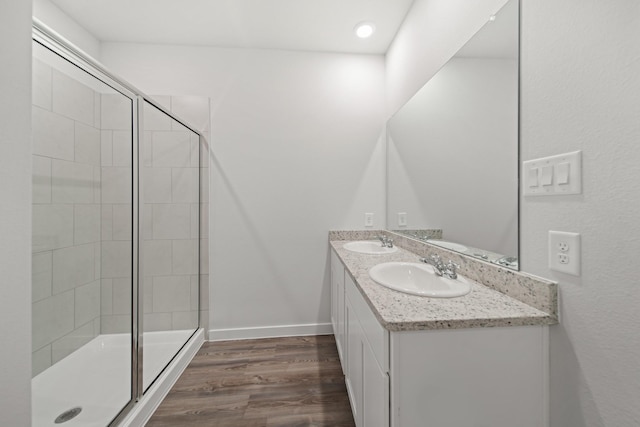 bathroom with wood-type flooring, a shower with shower door, and vanity