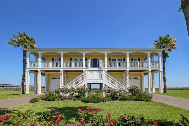 coastal home featuring covered porch and a front yard