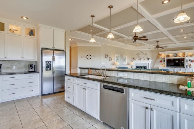 kitchen with coffered ceiling, stainless steel appliances, sink, dark stone countertops, and white cabinetry