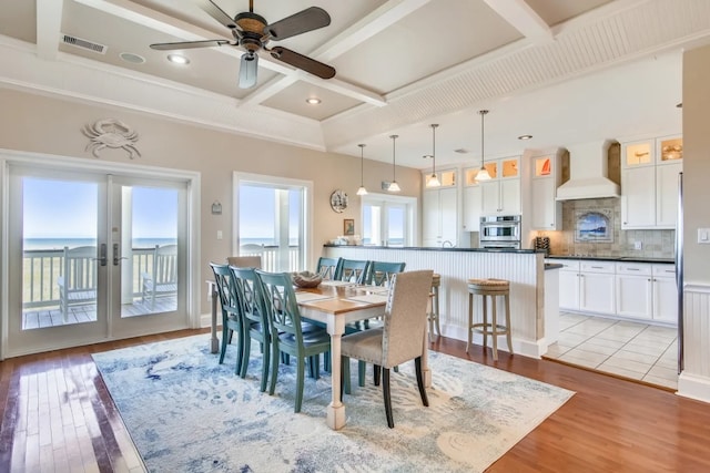 dining area featuring french doors, light wood-type flooring, ceiling fan, and coffered ceiling