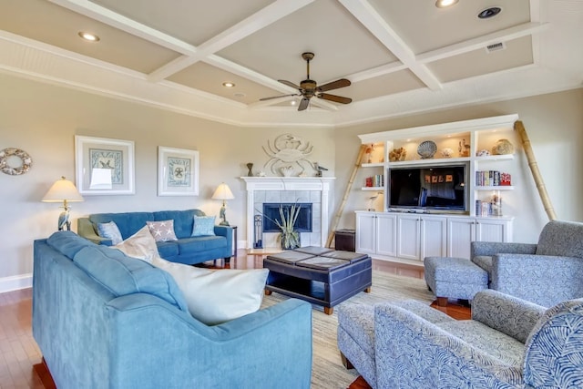 living room featuring a tile fireplace, coffered ceiling, hardwood / wood-style flooring, ceiling fan, and beam ceiling