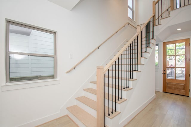 stairs with hardwood / wood-style floors and a high ceiling