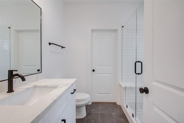 bathroom with tile patterned floors, vanity, toilet, and a shower with door