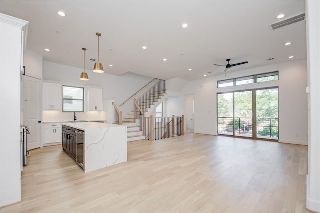 kitchen featuring white cabinets, light hardwood / wood-style flooring, ceiling fan, decorative light fixtures, and a kitchen island