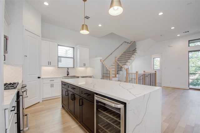 kitchen with decorative backsplash, decorative light fixtures, wine cooler, and white cabinets