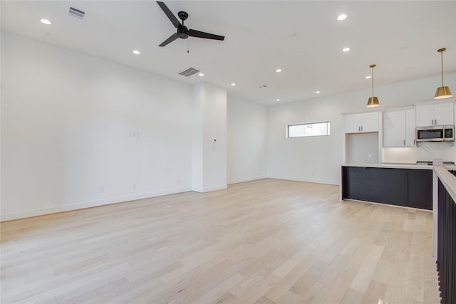 kitchen with decorative backsplash, white cabinetry, light hardwood / wood-style flooring, and decorative light fixtures