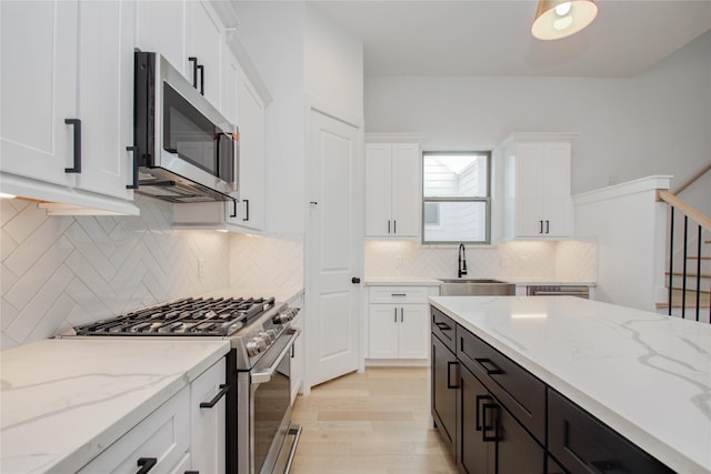 kitchen with white cabinetry, light stone countertops, sink, and appliances with stainless steel finishes