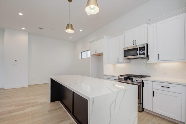 kitchen featuring white cabinetry, tasteful backsplash, decorative light fixtures, a kitchen island, and appliances with stainless steel finishes