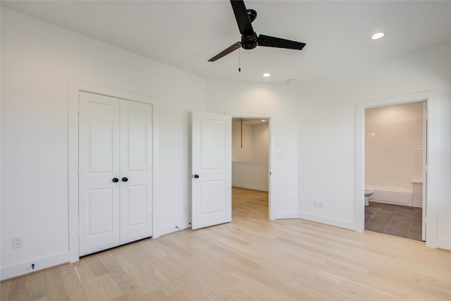 unfurnished bedroom with ceiling fan, a closet, light wood-type flooring, and ensuite bath