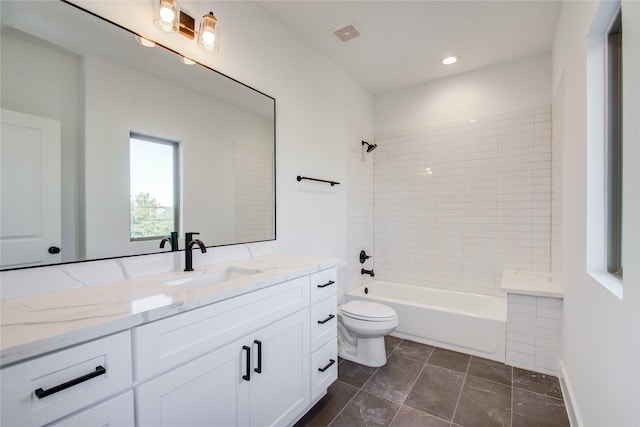 full bathroom with tiled shower / bath, vanity, and toilet