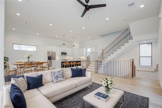 living room with a healthy amount of sunlight, ceiling fan, and light hardwood / wood-style floors