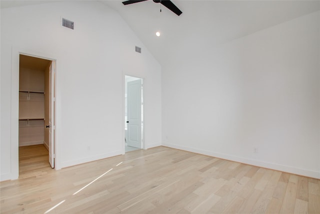 unfurnished bedroom featuring ceiling fan, light hardwood / wood-style flooring, high vaulted ceiling, a walk in closet, and a closet