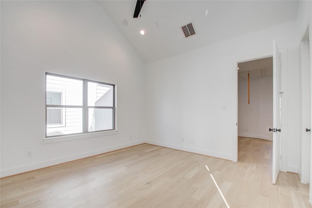 unfurnished room with light wood-type flooring and high vaulted ceiling