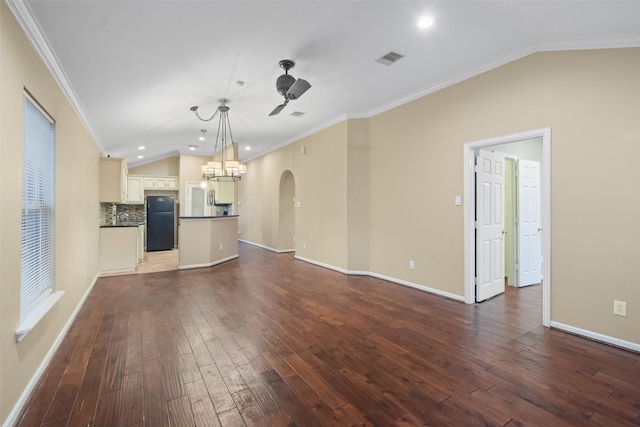 unfurnished living room featuring ceiling fan with notable chandelier, dark hardwood / wood-style floors, lofted ceiling, and crown molding