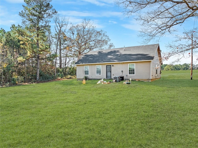 back of property with central AC and a yard