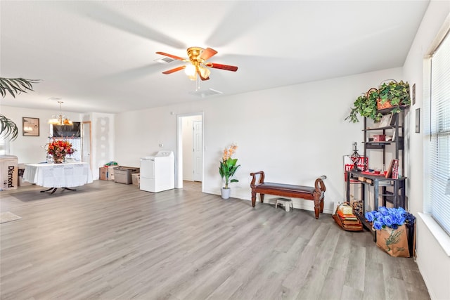 interior space with ceiling fan with notable chandelier, washer / dryer, and light wood-type flooring