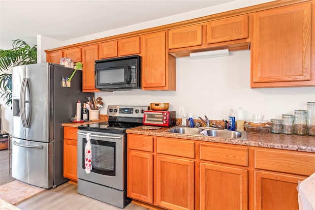 kitchen with stainless steel appliances, light hardwood / wood-style floors, and sink